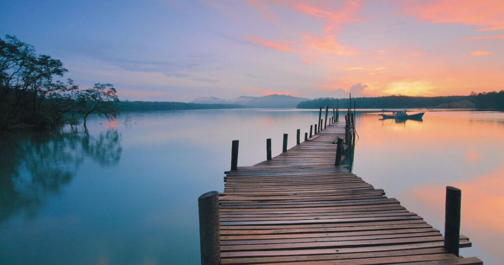 静かな湖に伸びる桟橋と、やさしく朝焼けが広がる穏やかな風景
