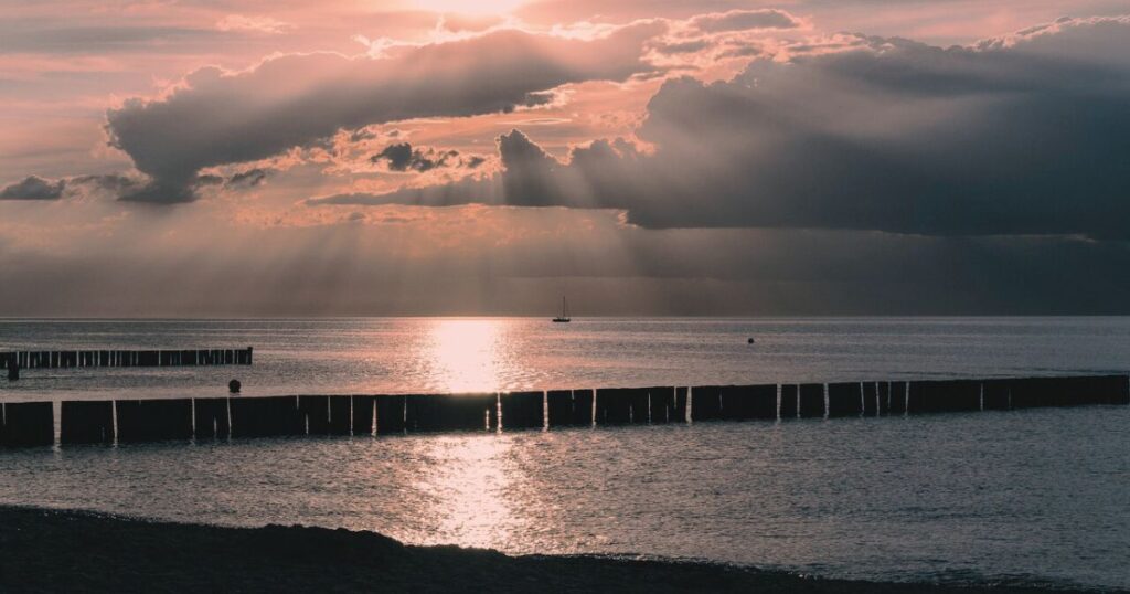 夕暮れの海に柔らかな光が差し込み、静かに希望を感じさせる風景