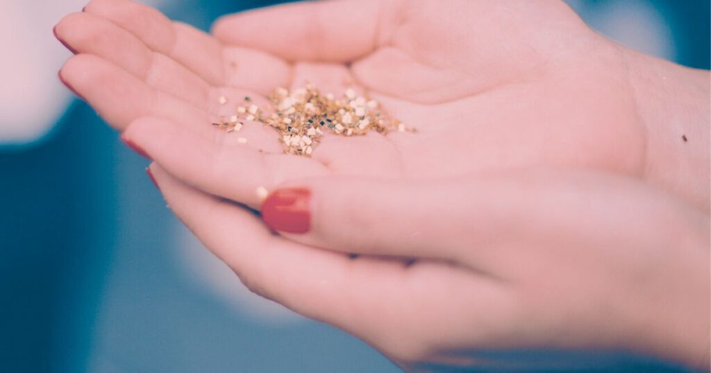 女性の手のひらに広がる金色の粒が、見えにくい優しさのサインを象徴するように柔らかく光っている写真
