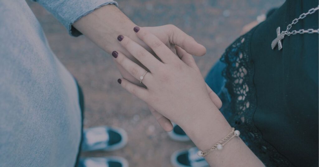 そっと手を重ね合う男女の手元。寄り添う想いが静かに伝わる情景