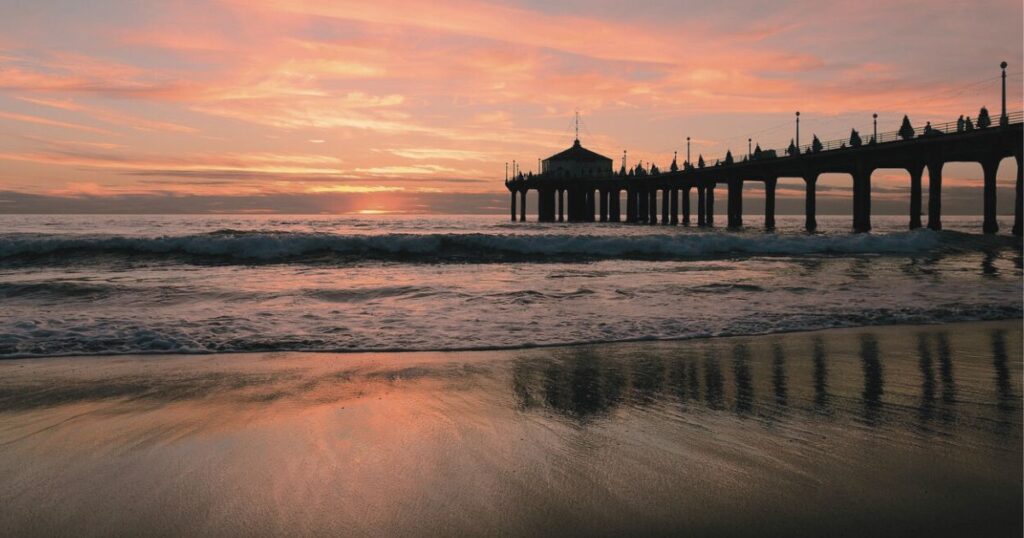 夕日が沈む浜辺と桟橋のシルエットが映る静かな風景