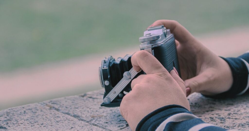 レトロカメラを静かに構える女性の手元の写真
