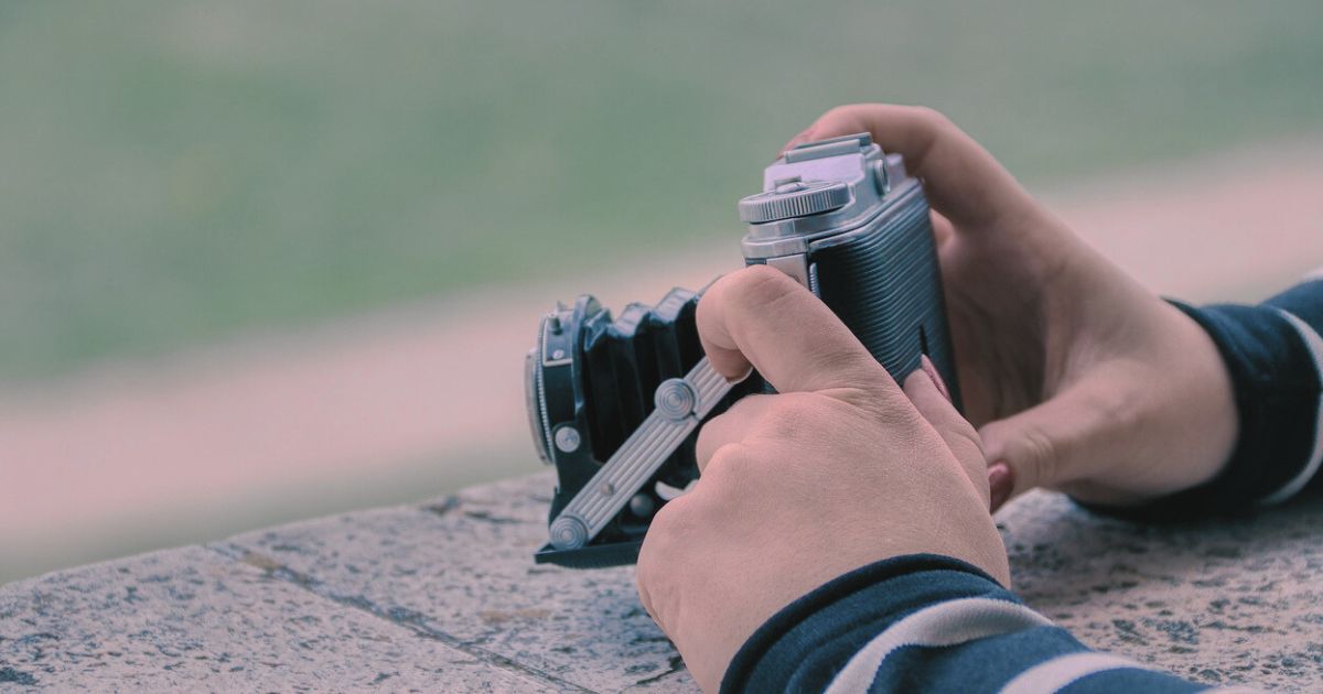 レトロカメラを静かに構える女性の手元の写真