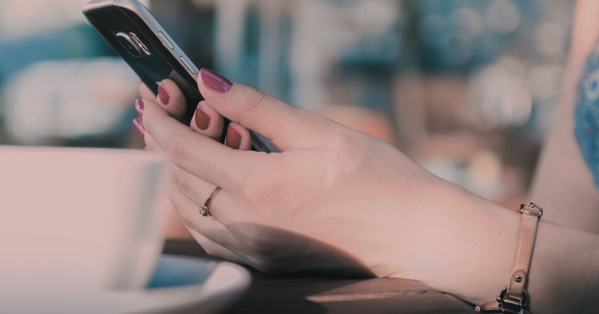 女性がスマートフォンをそっと持ちながら画面を見つめる手元の写真。彼の沈黙に不安を感じる瞬間をイメージした構図。