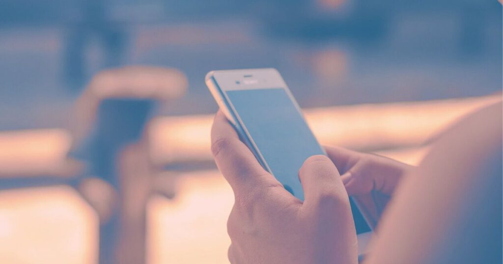 スマホを見つめる女性の手元。返信のない彼を待つ静かな時間をイメージした写真。